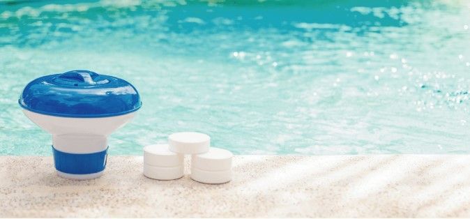 Un limpiador de piscinas azul y blanco está sentado al lado de una piscina.