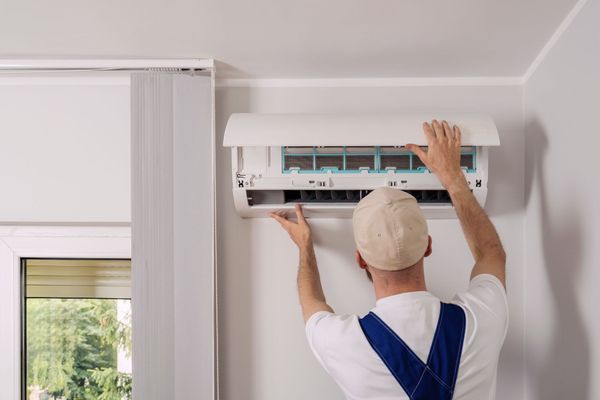 Technician installing a wall-mounted air conditioner in a bright room Technician installing a wall-mounted air conditioner in a bright room