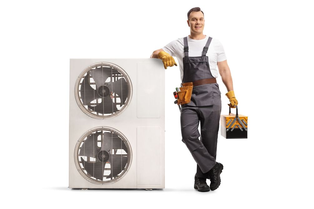Technician in gray overalls stands beside a white appliance, holding a toolbox and leaning on it. Technician in gray overalls stands beside a white appliance, holding a toolbox and leaning on it.