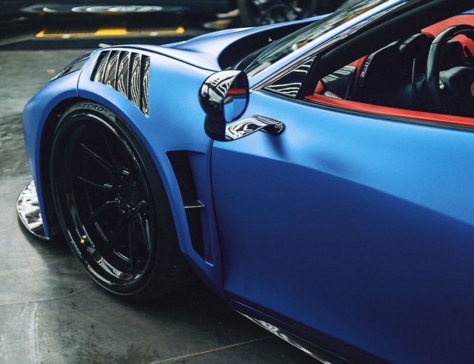 A blue sports car with black wheels is parked in a garage.