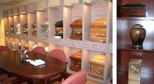 A funeral home showroom with caskets on display, wooden table and chairs.