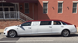 White limousine with a burgundy roof parked in front of a building.