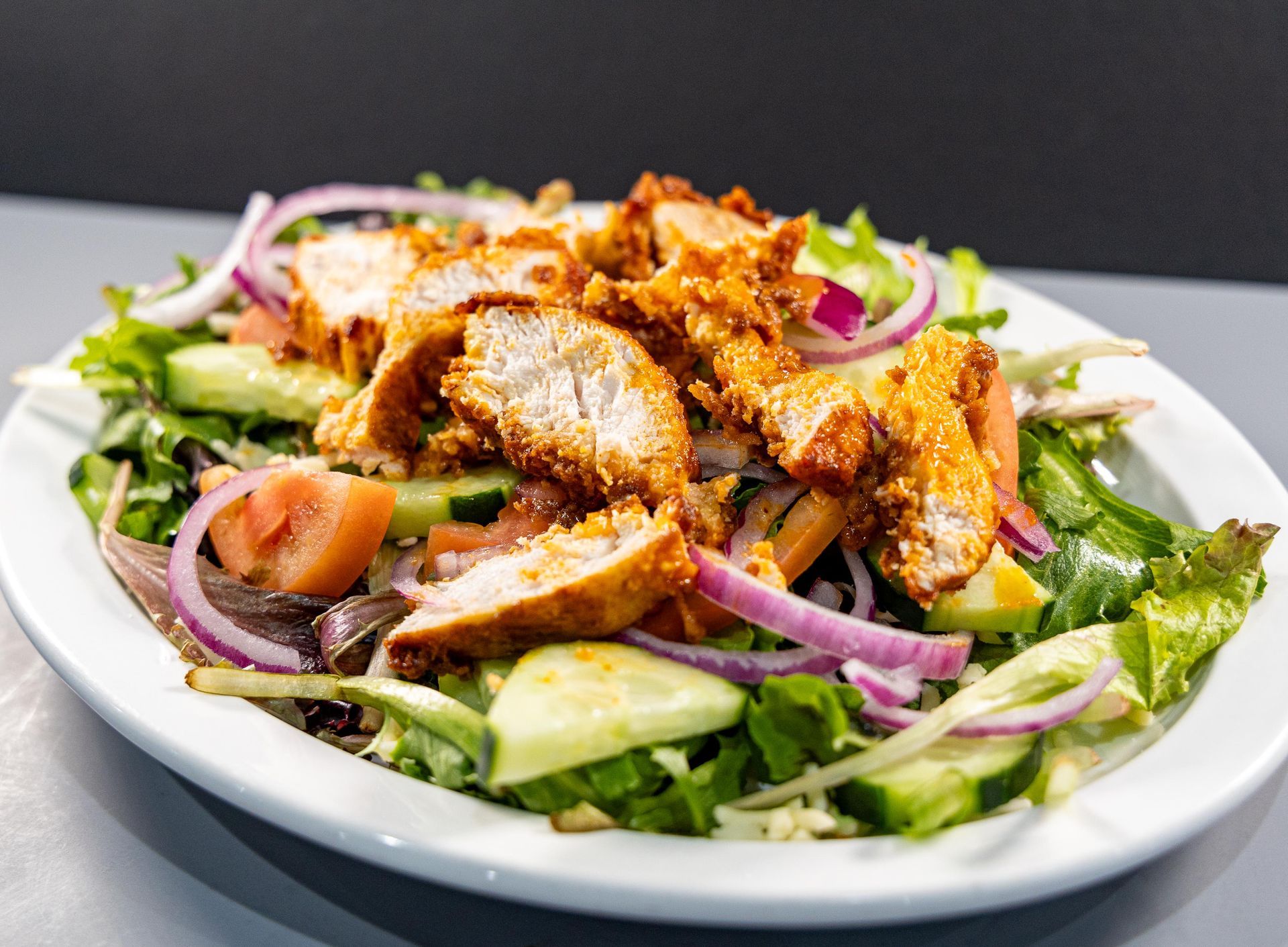 A white plate topped with a salad with chicken and vegetables.