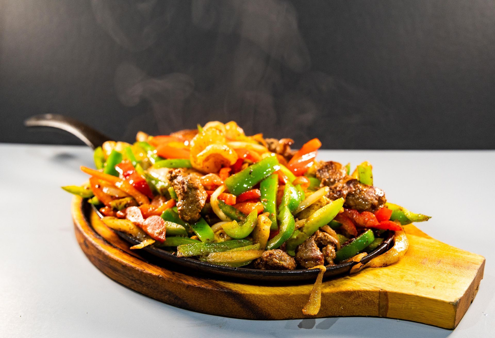 A plate of food with meat and vegetables on a wooden cutting board.