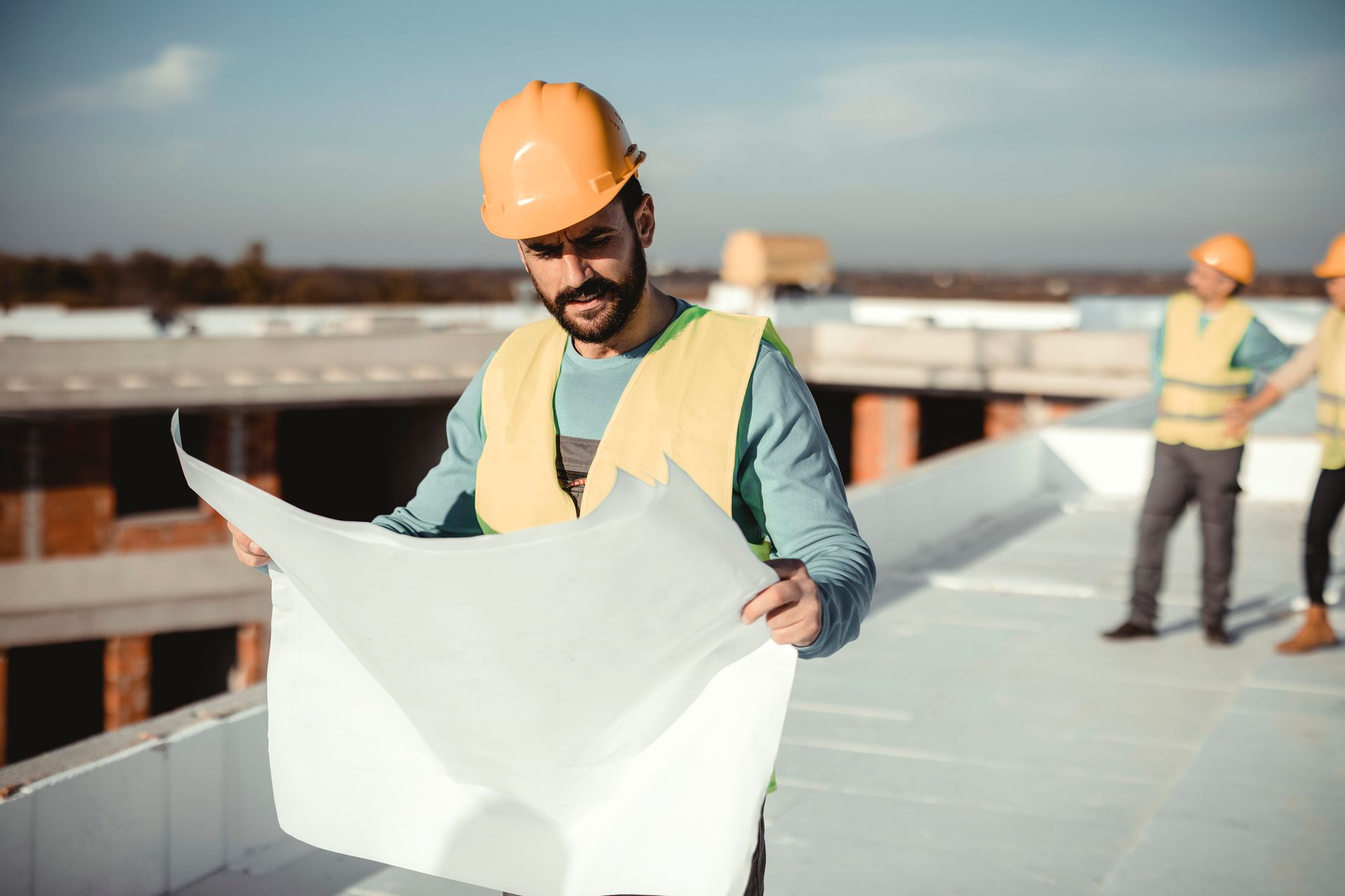 A construction worker is looking at a blueprint at a construction site.