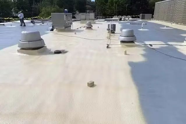 A man is standing on top of a white roof.