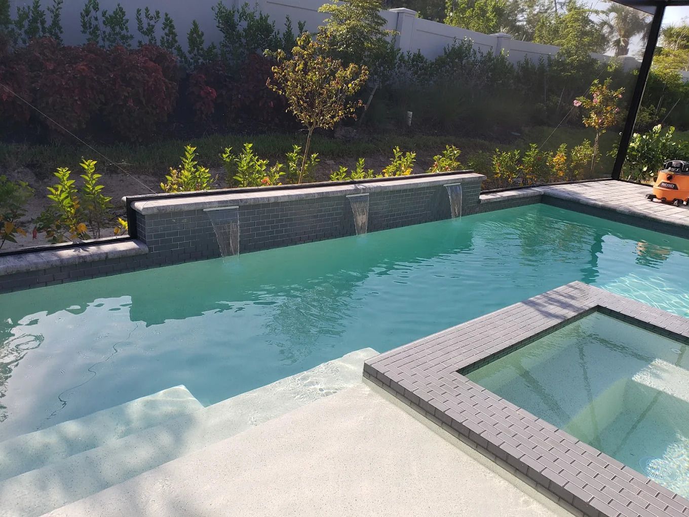 A large swimming pool with a waterfall in the backyard.
