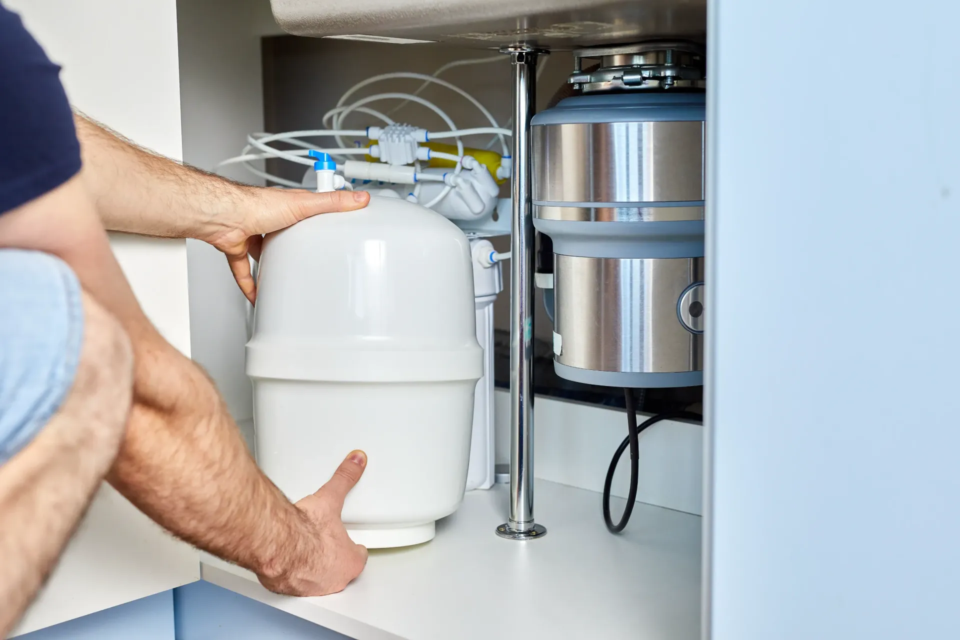 Person installing a white water filter under a kitchen sink. — Fixtures & Fittings In Tweed Heads South, NSW