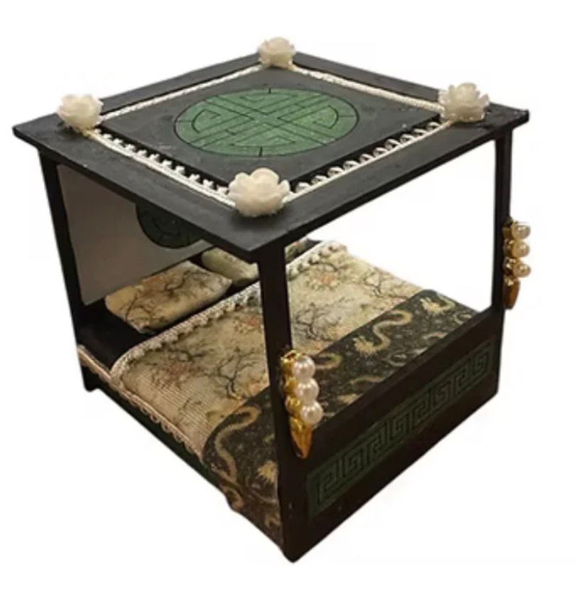 Miniature black canopy bed with floral and green accents.