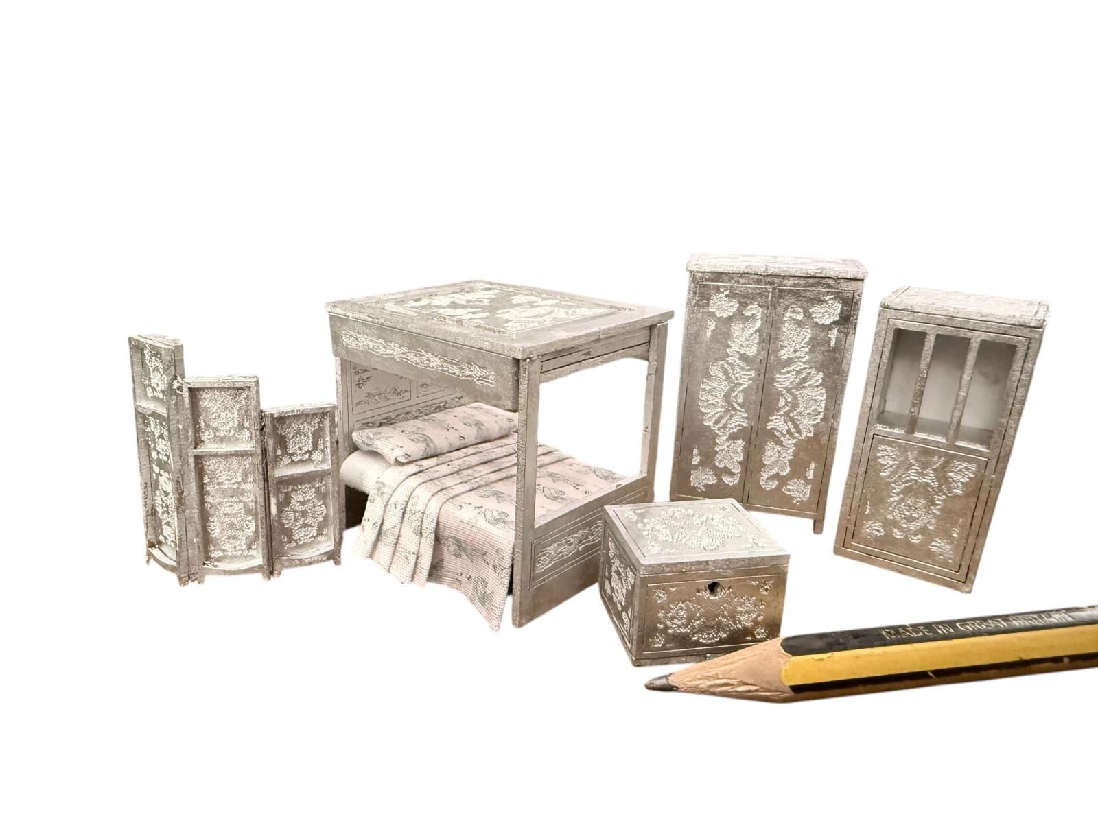 Miniature carved furniture set with pencil for scale.