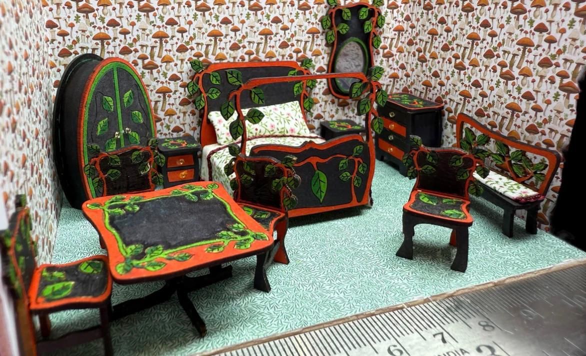 Miniature bedroom with black furniture, orange accents, and green leaf detailing; mushroom wallpaper.