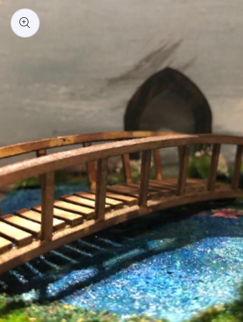 Wooden bridge over blue water with a blurred background of a dark arch.