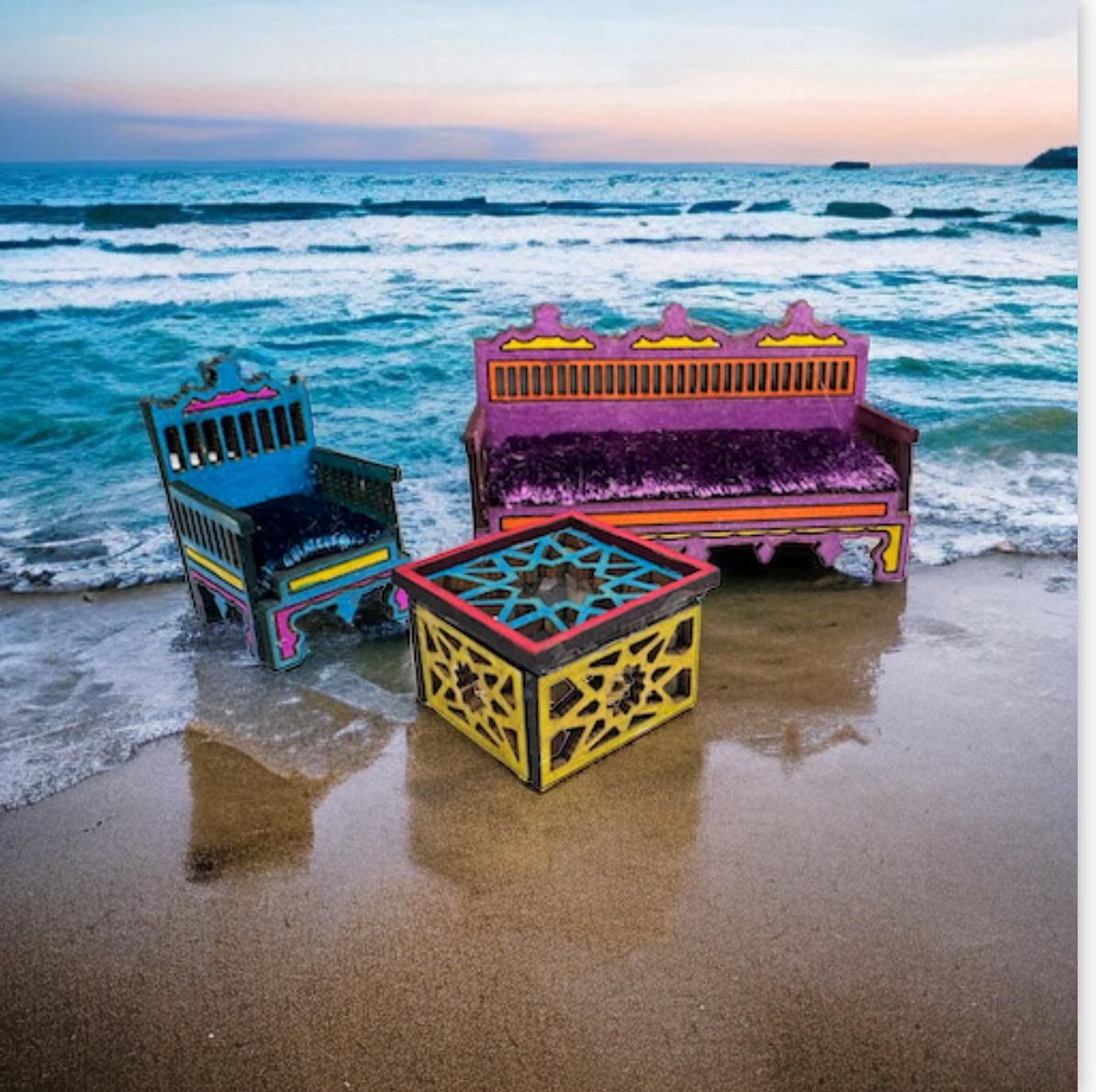 Colorful furniture set on a sandy beach with ocean waves.