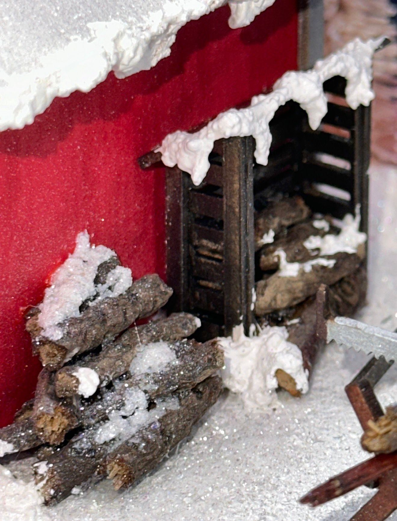 Red building with woodpile covered in snow.