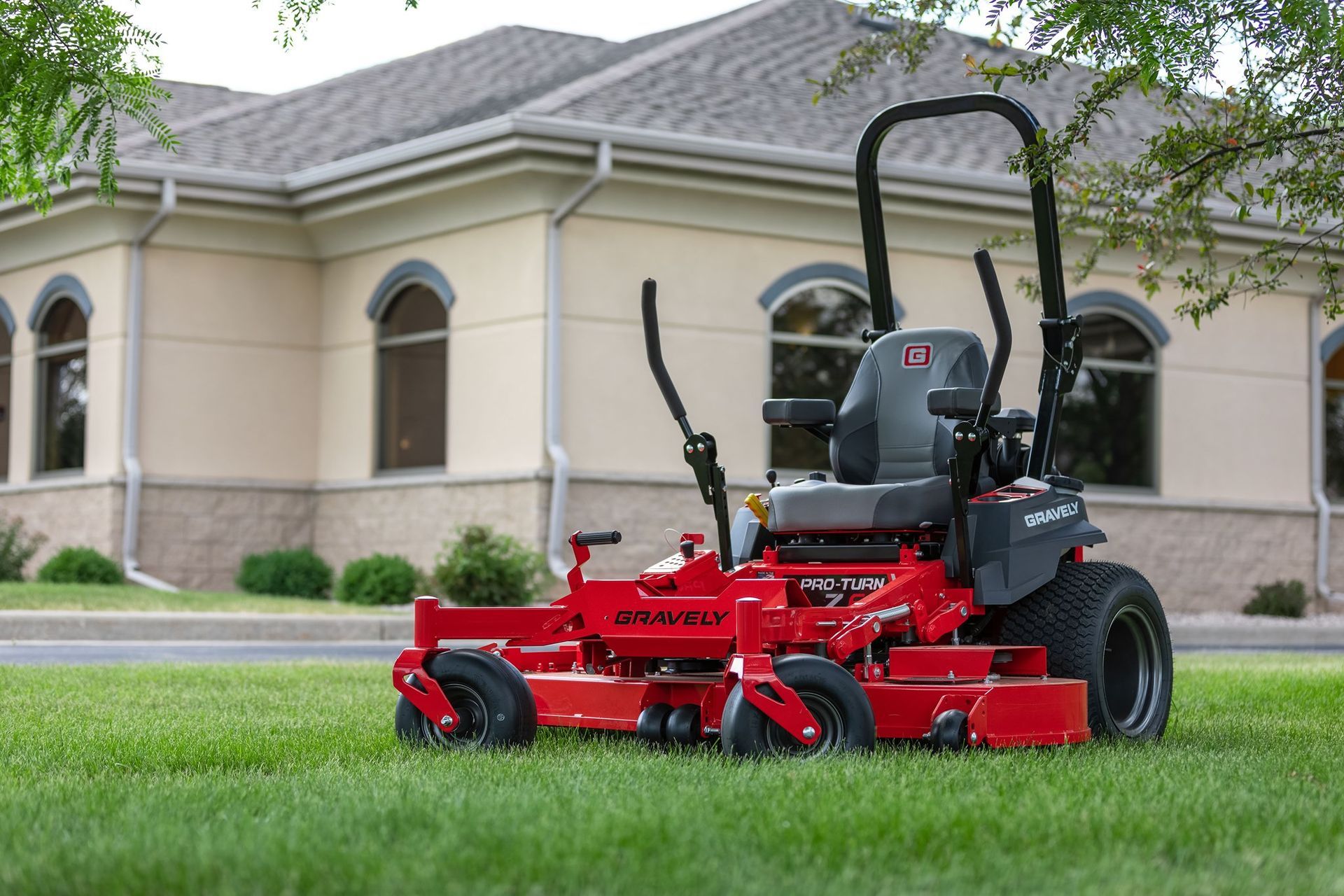 Red zero-turn lawnmower on a green lawn in front of a building with arched windows.
