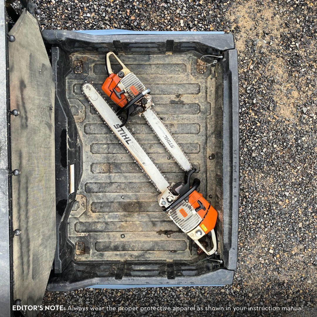 Two Stihl chainsaws in a truck bed, visible dirt, orange and white.