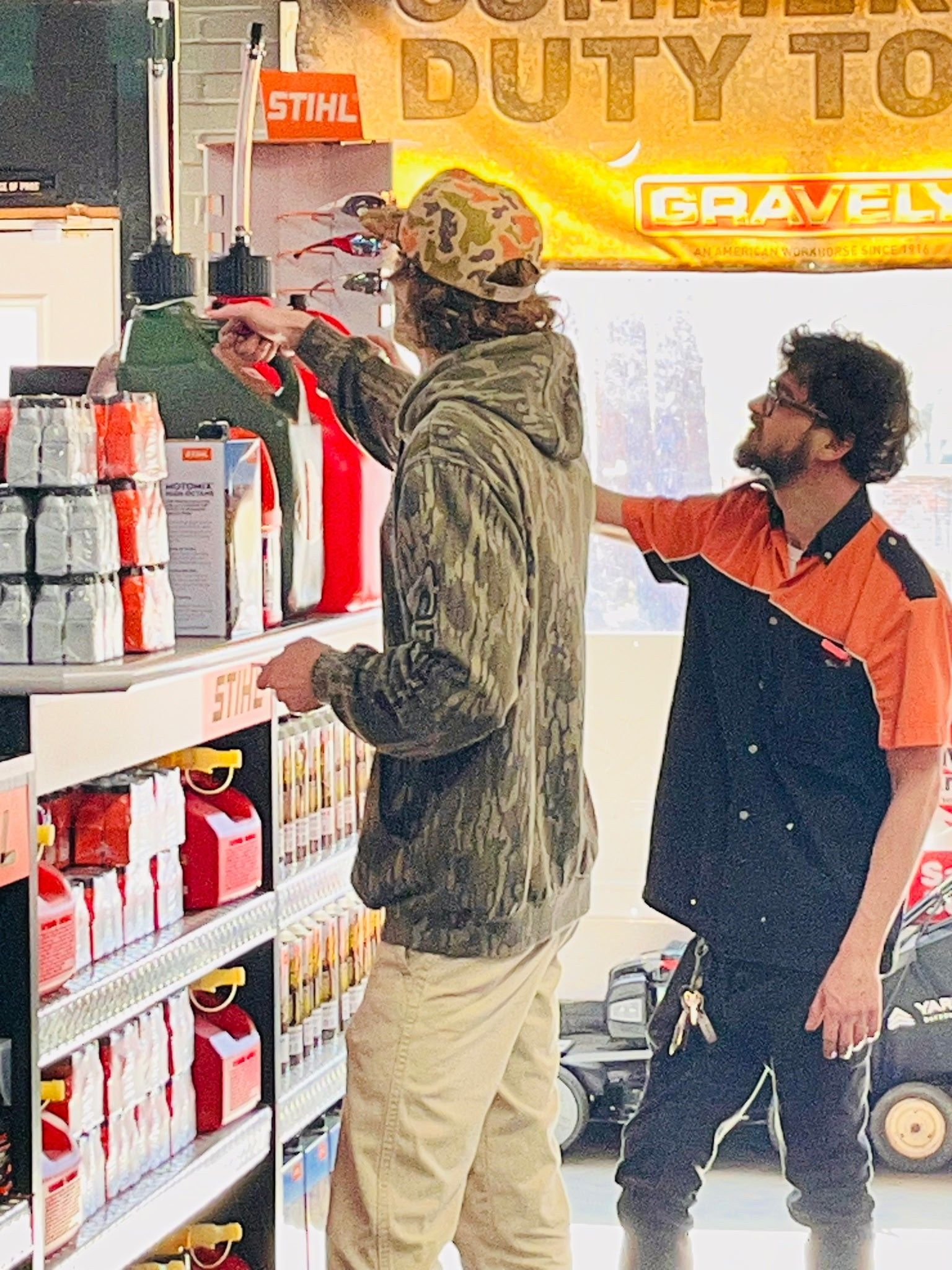 Man using a pressure washer on a white deck, orange and white machine, bright outdoors.