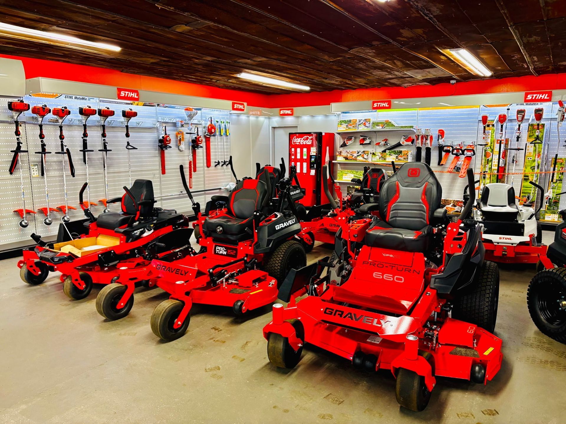 Lawn tools displayed on green grass, including trimmers, blowers, and pole saws.