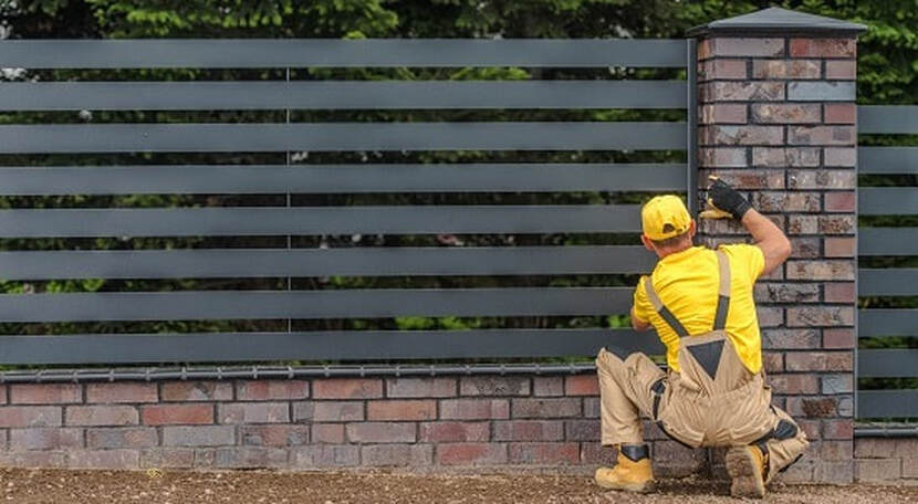 A fencing labourer is installing a black metal fence for a residential property in Ballarat VIC.