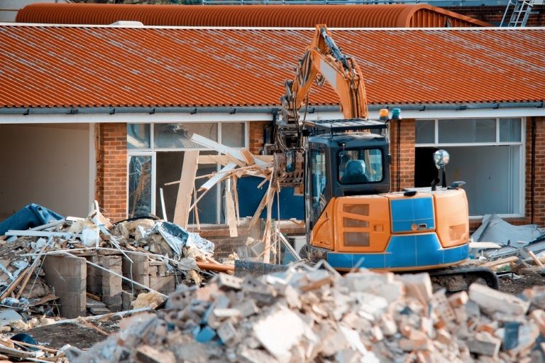 A bulldozer is demolishing a building with a pile of rubble in front of it. — Al's Excavation in Sunshine Coast, QLD