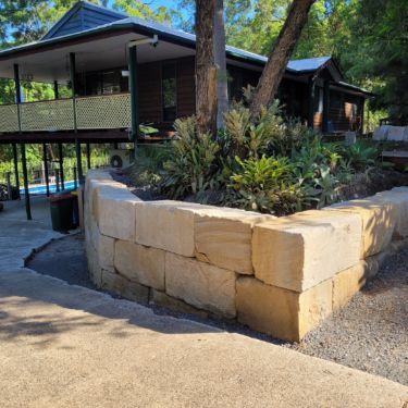 A house with a stone wall in front of it surrounded by trees. — Al's Excavation in Sunshine Coast, QLD