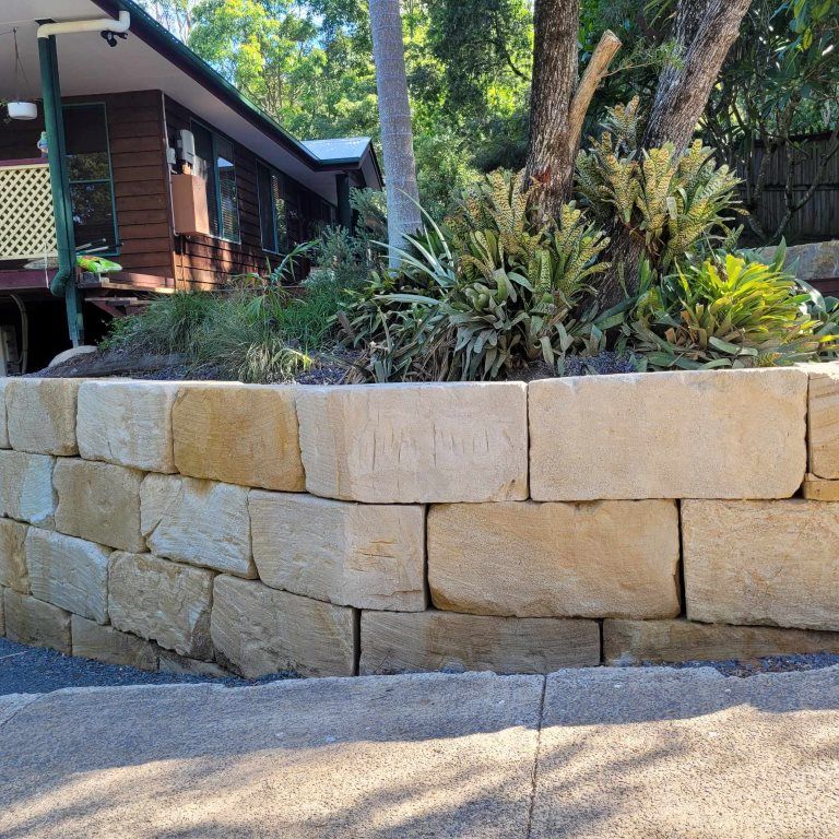 A Stone Wall With a House in the Background — Al's Excavation in Bridges, QLD