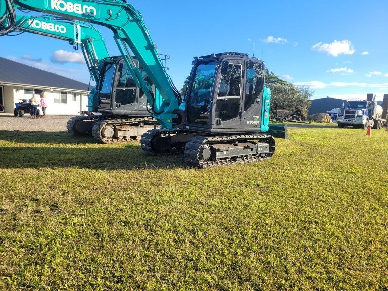 Two Kobelco Excavators Are Parked in a Grassy Field — Al's Excavation in Bridges, QLD