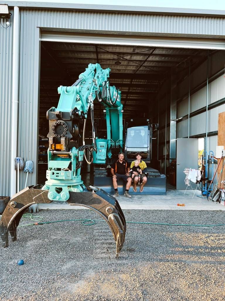 A Couple of People Are Sitting in Front of a Large Machine in a Garage — Al's Excavation in Bridges, QLD