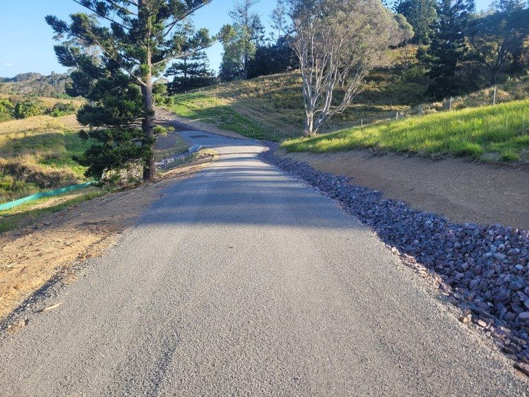 A Road Going Through a Grassy Hillside With Trees on Both Sides — Al's Excavation in Bridges, QLD