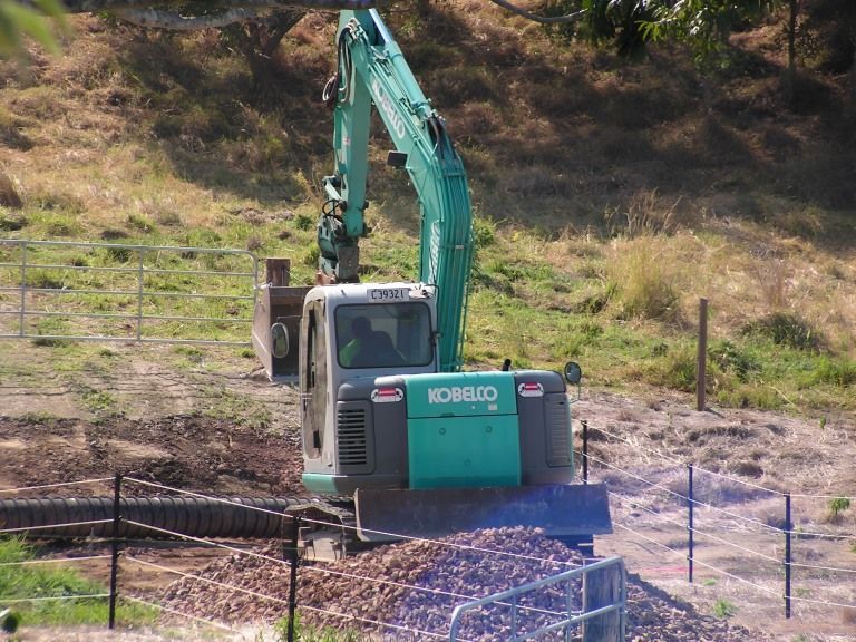 A Kobelco Excavator is Moving Dirt in a Field — Al's Excavation in Bridges, QLD
