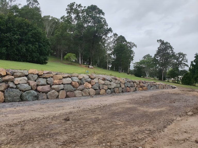 A Large Rock Wall is Sitting on the Side of a Dirt Road — Al's Excavation in Bridges, QLD