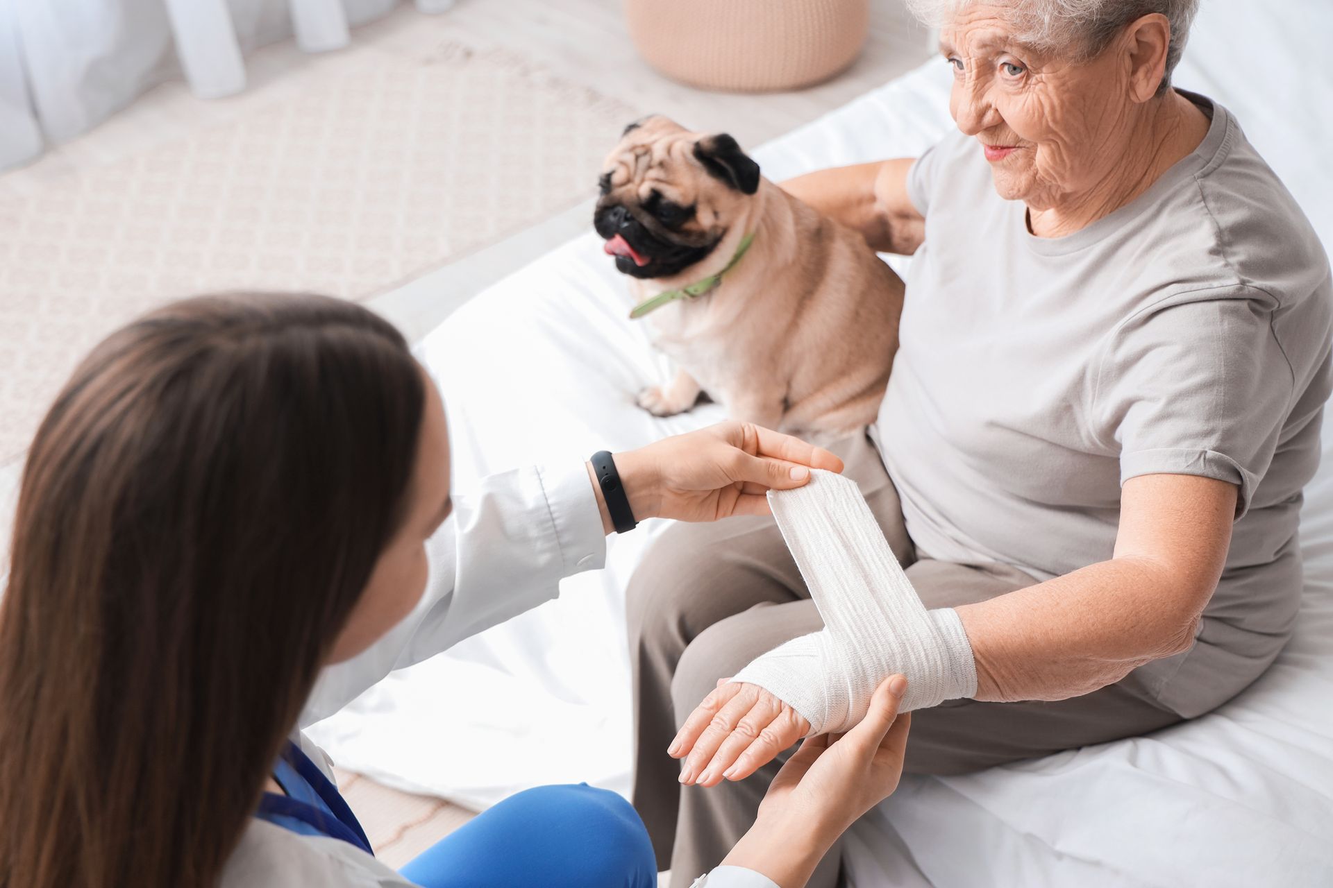 Home caregiver with senior woman bandaging her wrist.