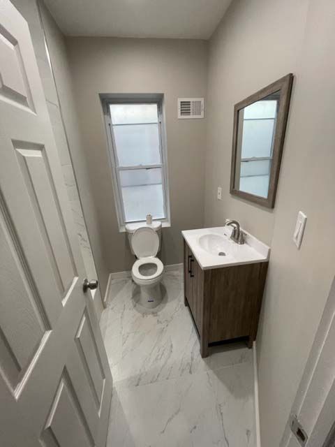 A bathroom with a toilet , sink and mirror.