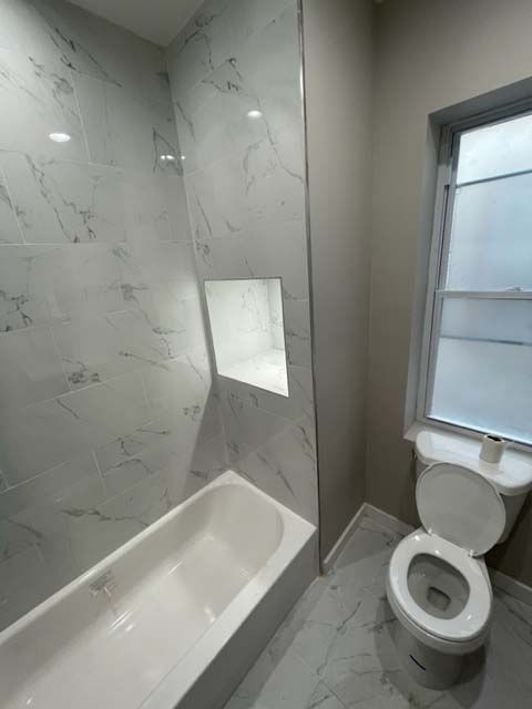 A bathroom with a toilet , tub and shower.