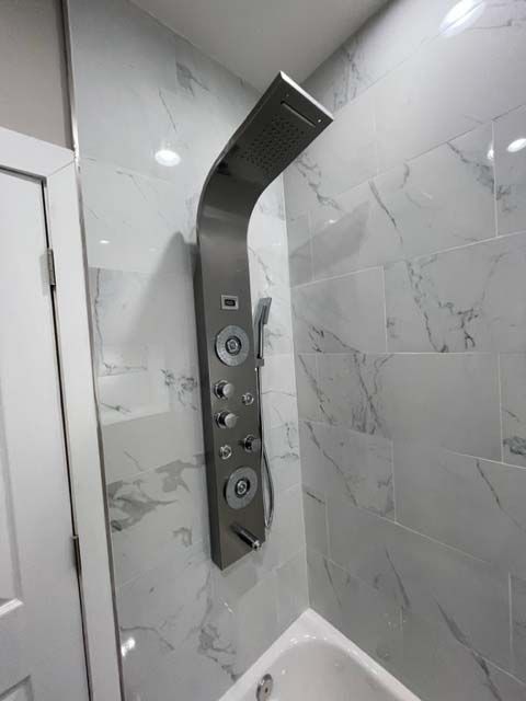 A shower head is mounted to the wall of a bathroom next to a bathtub.