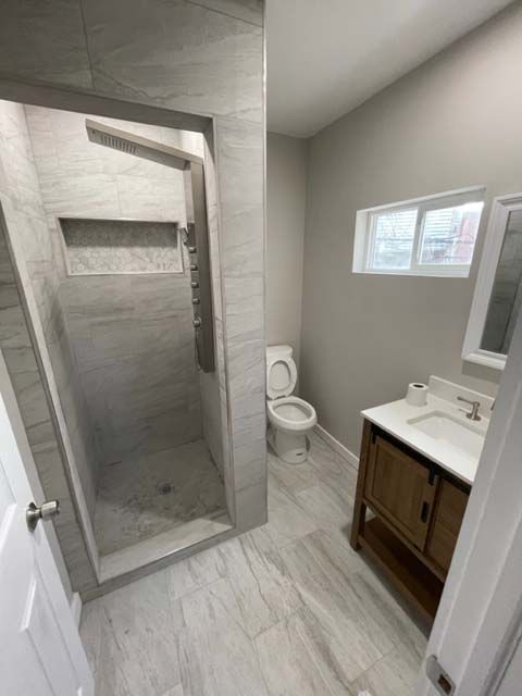 A bathroom with a toilet , sink and shower.