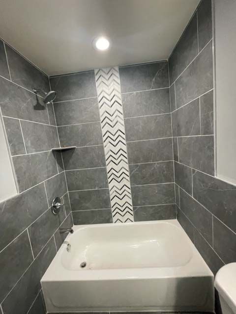 A bathroom with a bathtub , toilet and shower.