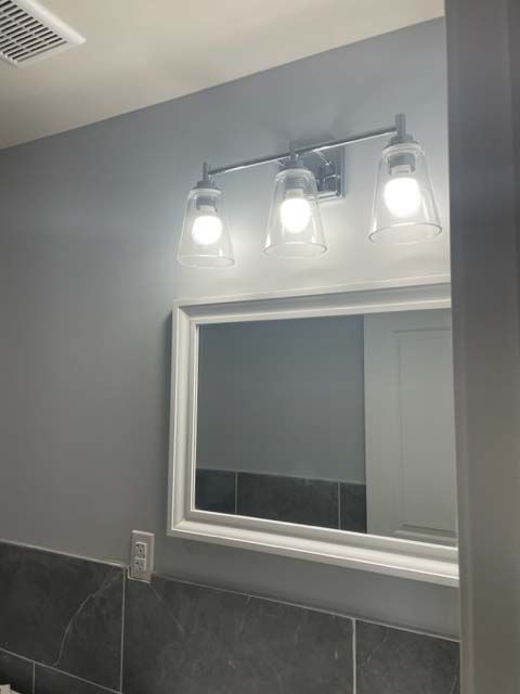 A bathroom with a mirror and lights on the wall.