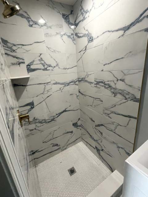A bathroom with marble walls and a walk in shower