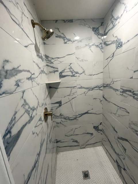 A shower with marble tiles and a shower head