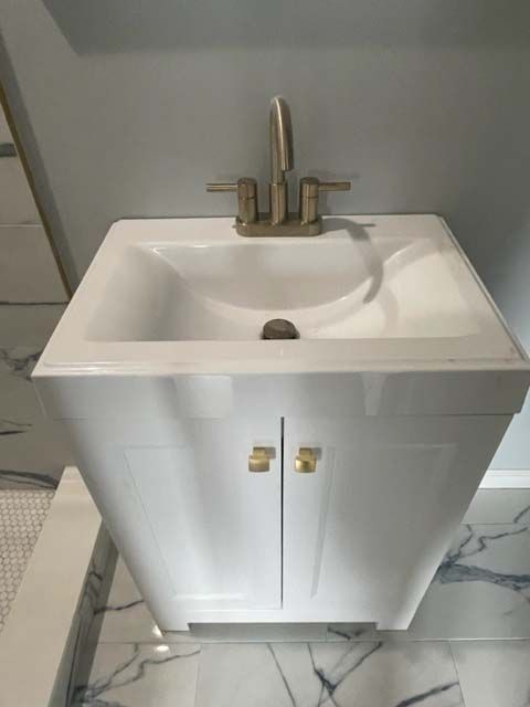 A bathroom sink with two doors and a faucet.
