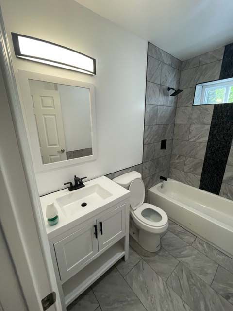 A bathroom with a toilet , sink and bathtub.