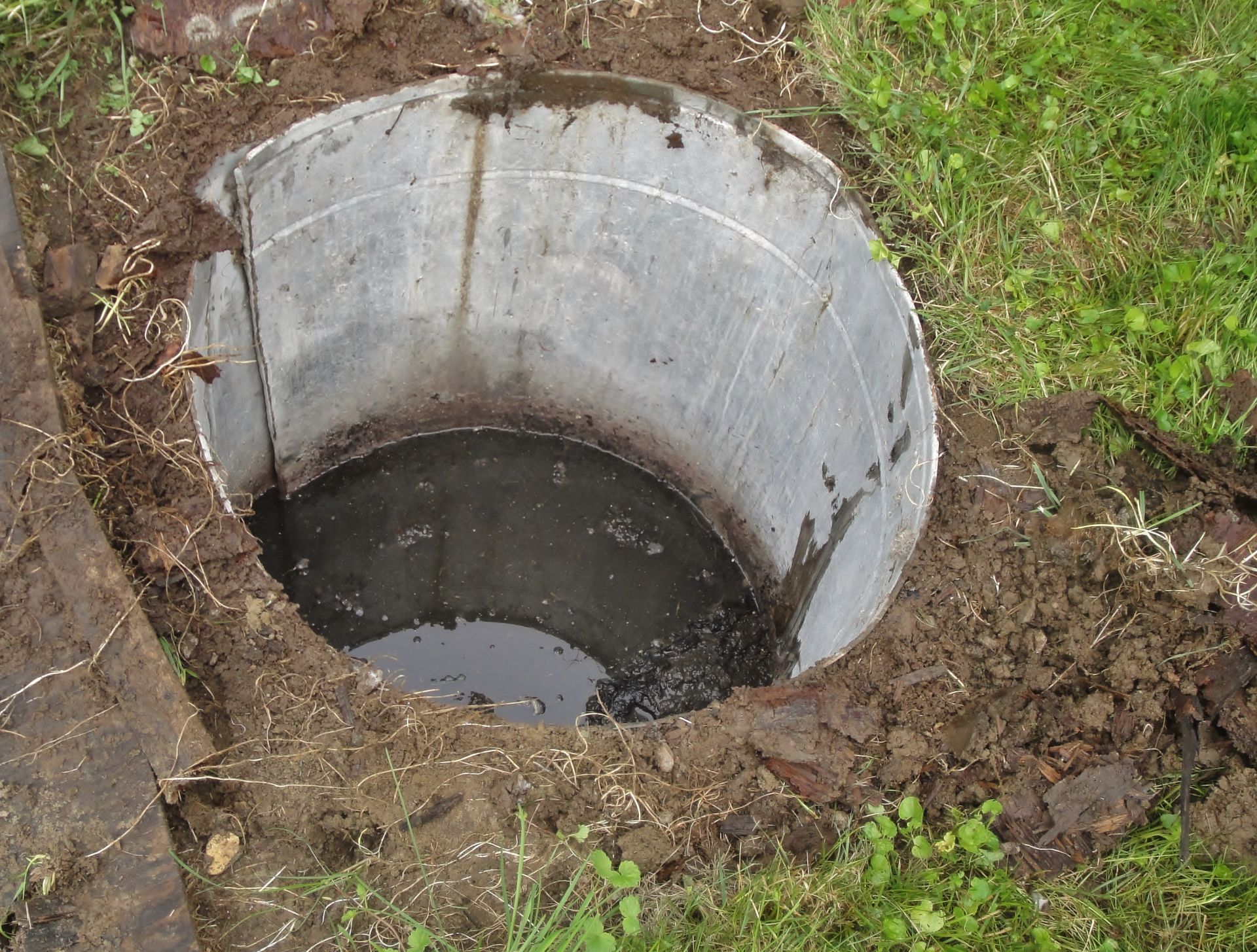 Concrete septic tank in a residential yard in Englewood, FL, is open for a septic pumping by Southern Sanitary Systems, Inc.