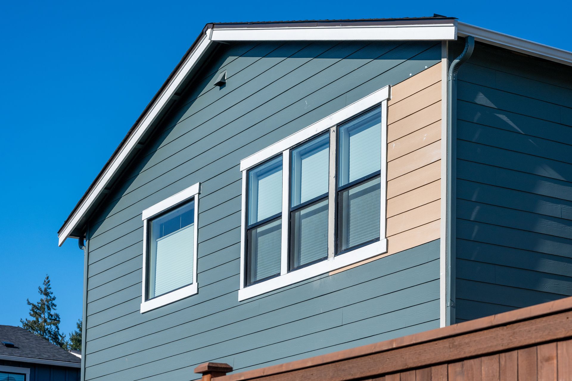House exterior with blue siding and windows showing residential home siding and window trim details.
