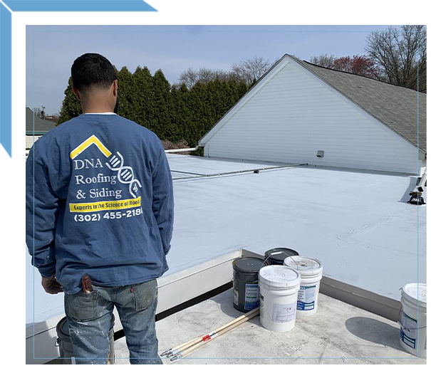 Worker On Flat Roof With Roofing Supplies