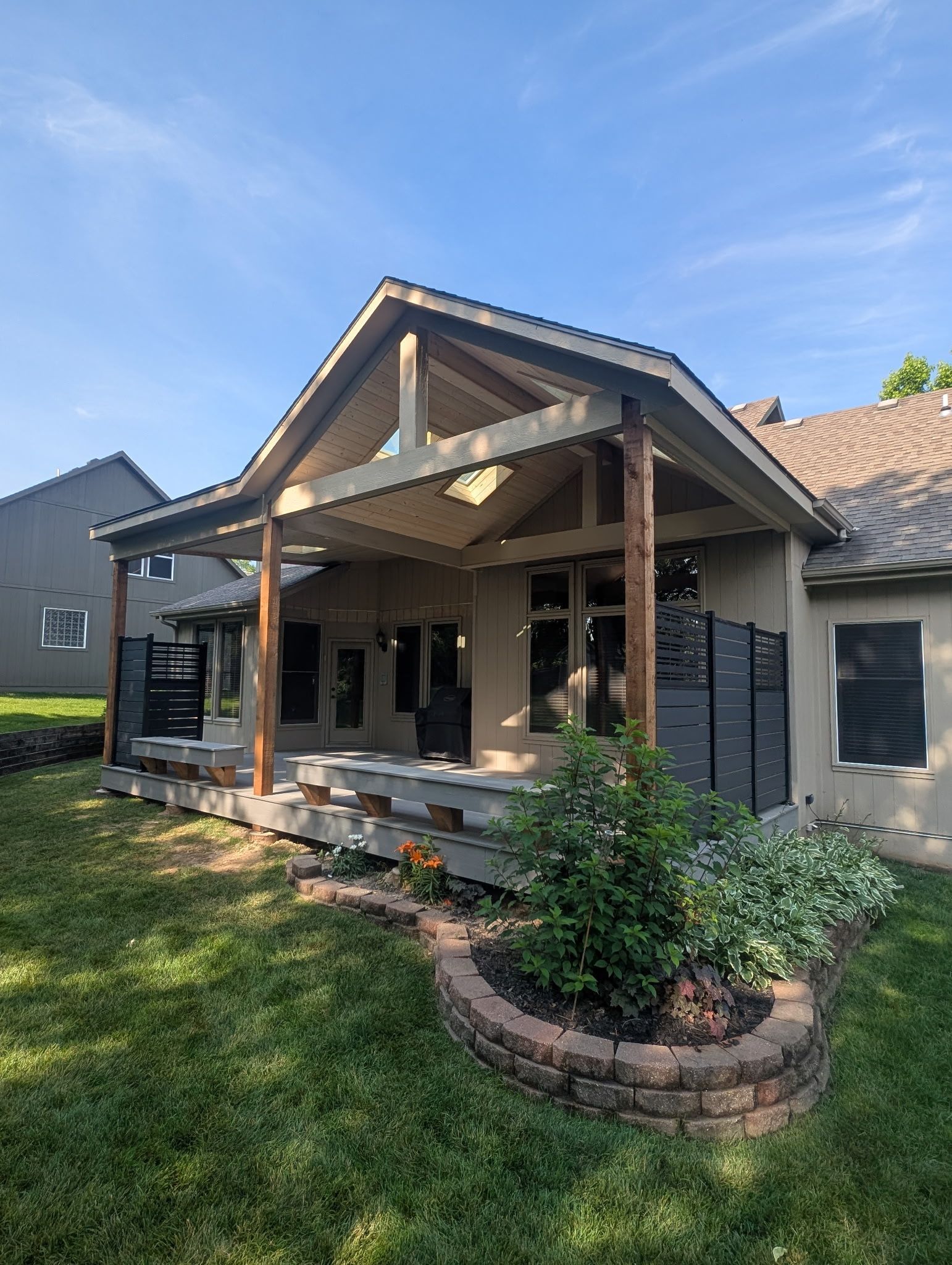 Covered patio with wooden posts and trim, steps, and a landscaped yard.