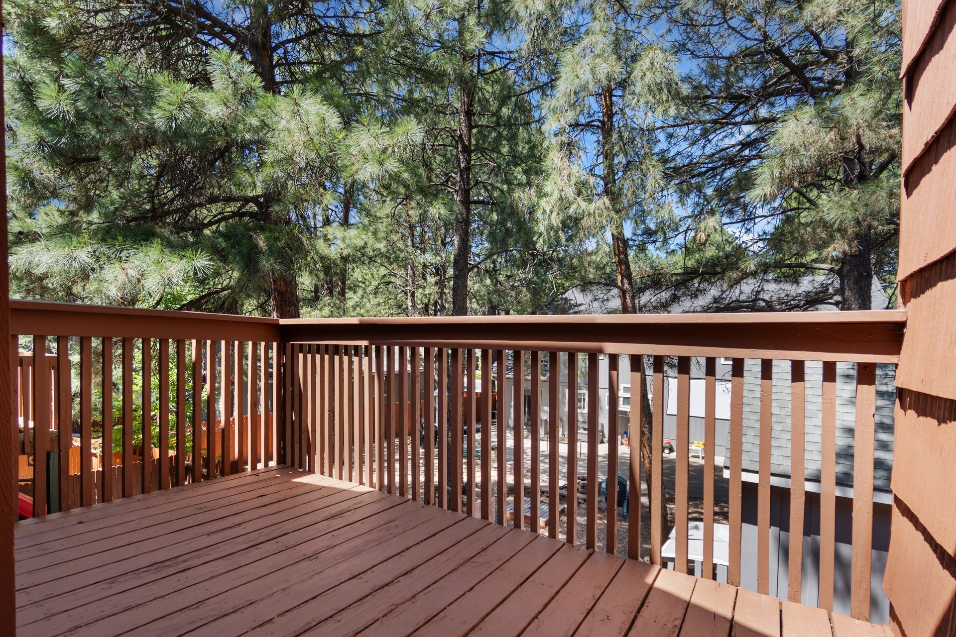 A beautiful wooden deck complete with a railing and trees in the background.