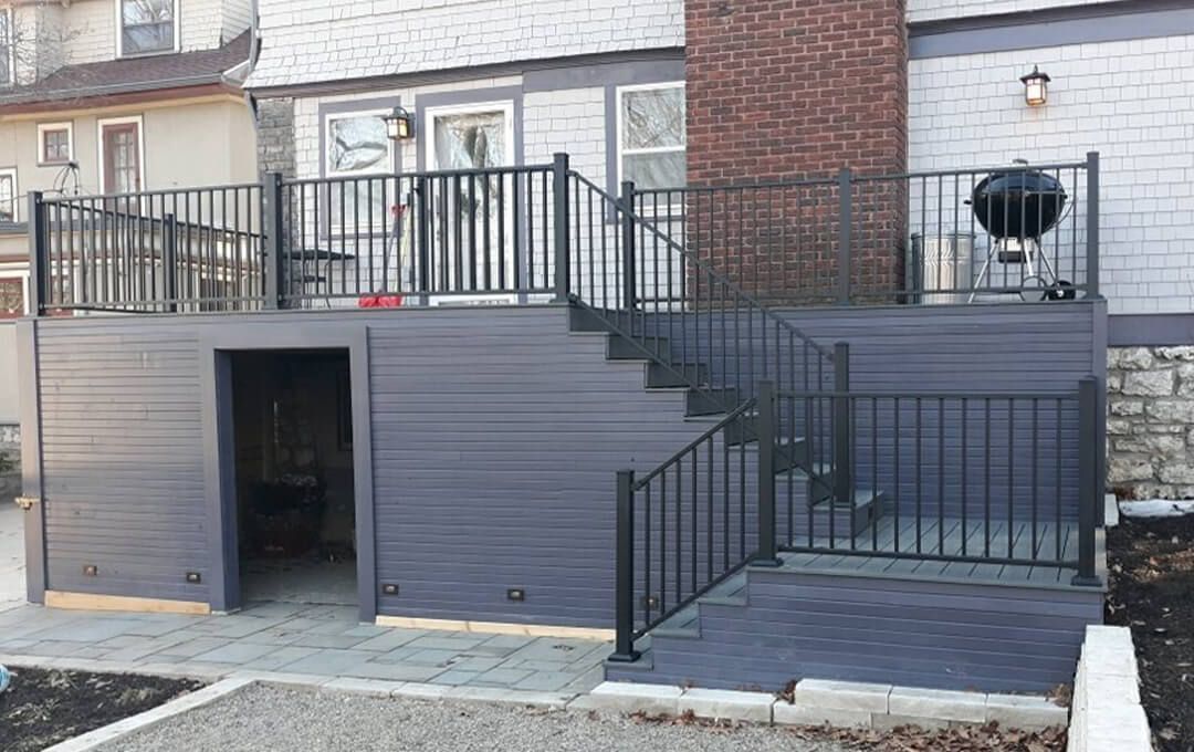 There is a deck with stairs leading up to it and a grill on it.