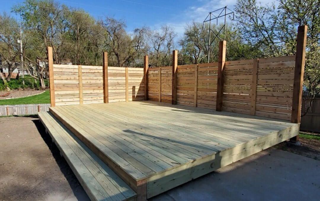 A wooden stage with a wooden fence in the background.