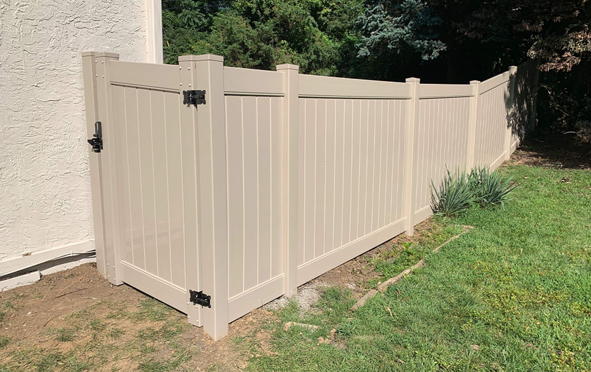 A white vinyl fence with a gate in the backyard of a house.